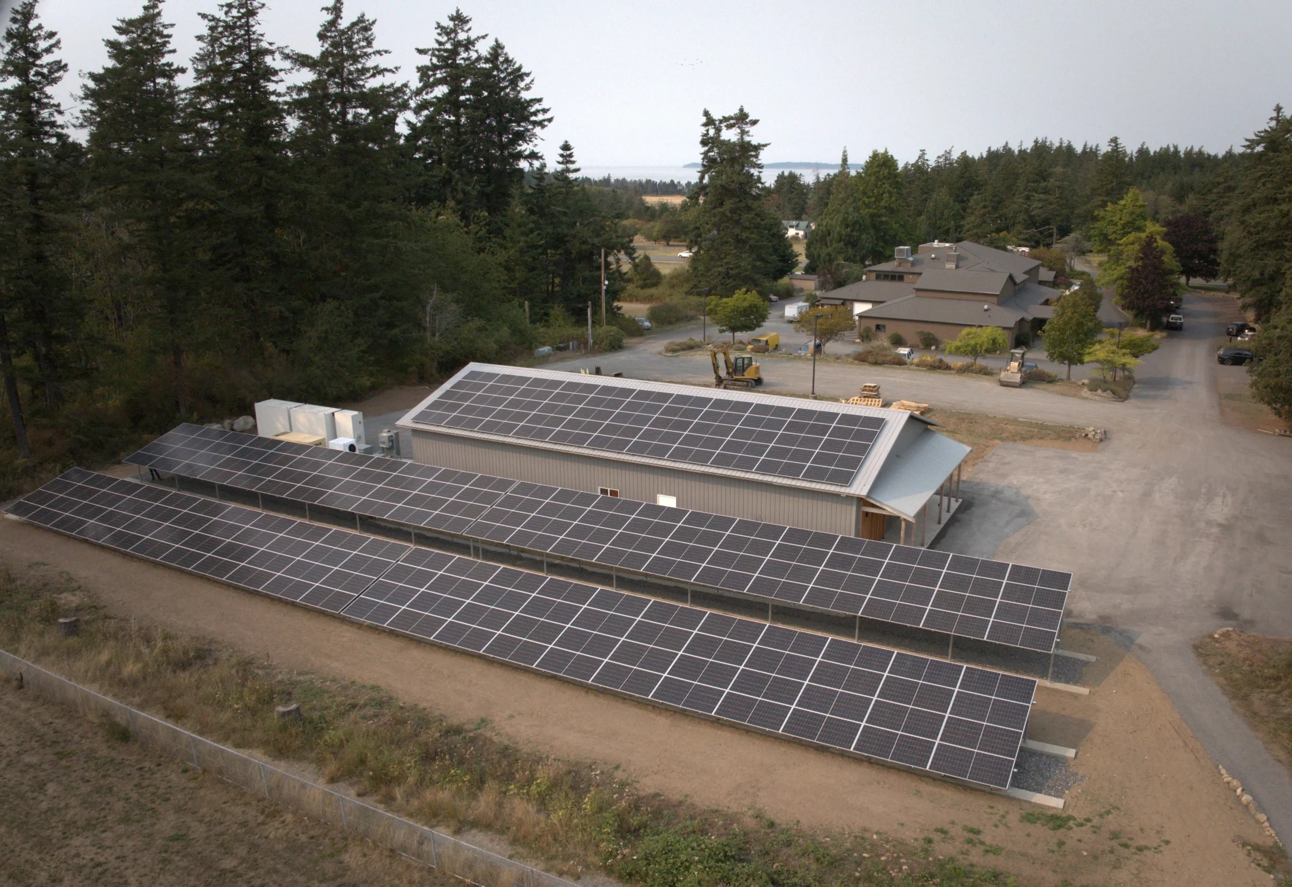 Aerial view of a solar panel array powering a building surrounded by trees